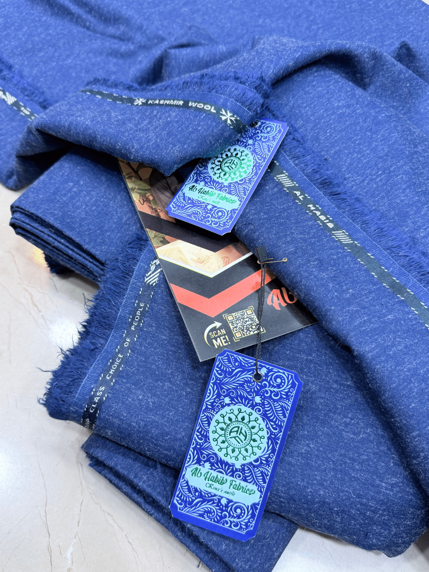 Blue fabric with tags on a light wooden surface**AlHabibFabrics, AlHabibWinter, King'sOutfit, TopClassChoice, AlHabib, KashmirWool, WoolFabric, PremiumWool, SoftWool, WarmFabric, UnstitchedWool, SuitingWool, Men'sSuiting, UnstitchedFabric, ShalwarKameezFabric, KurtaShalwarFabric, Men'sDressMaterial, PremiumSuit, LuxuryMenswear, ElegantFabric, FormalWearMen, BestWinterFabric, NavyBlue, CharcoalGrey, DarkBrown, DeepBlue, MaroonFabric, GreySuit, PlainColors, PakistaniFabric, Menswear, WinterWearPakistan, Lates